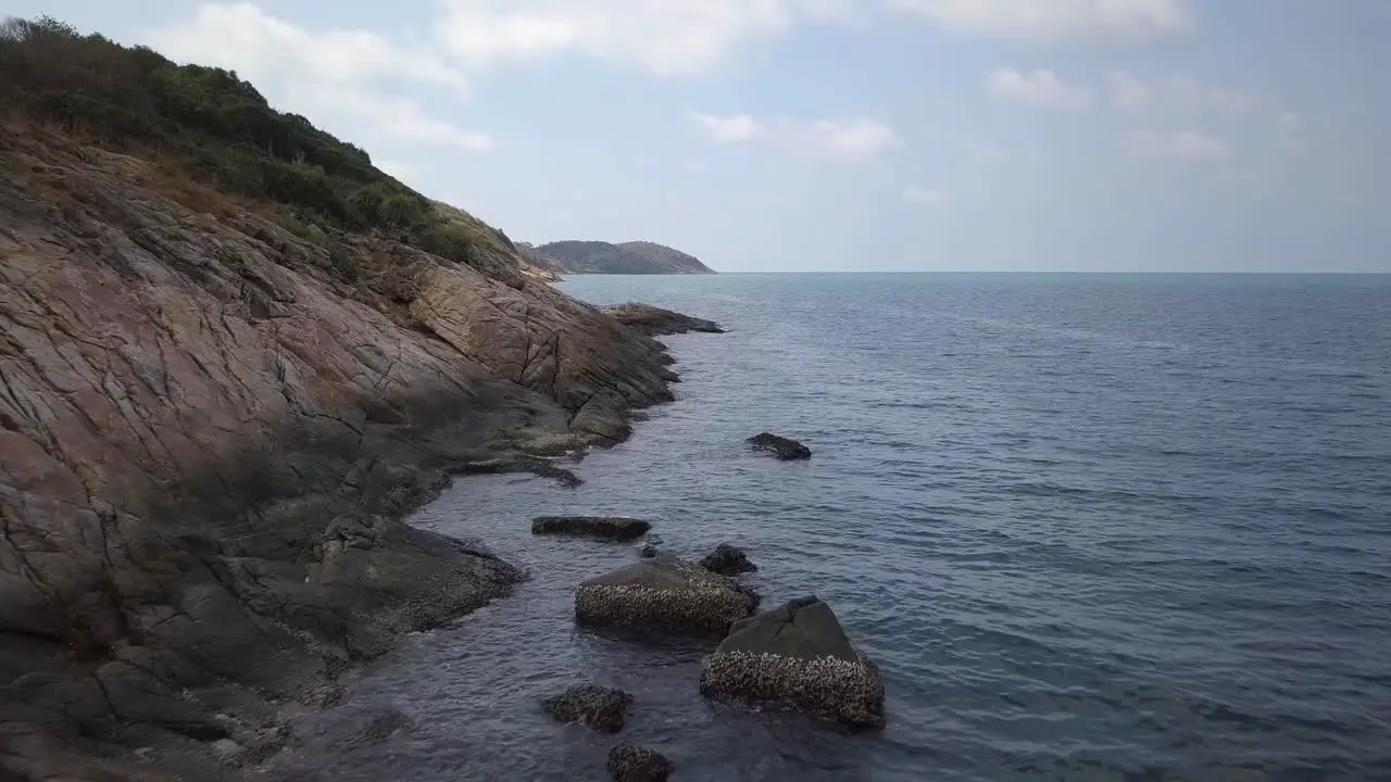 Aerial low alltitude landscape shot over the rocks steep shore and the ocean