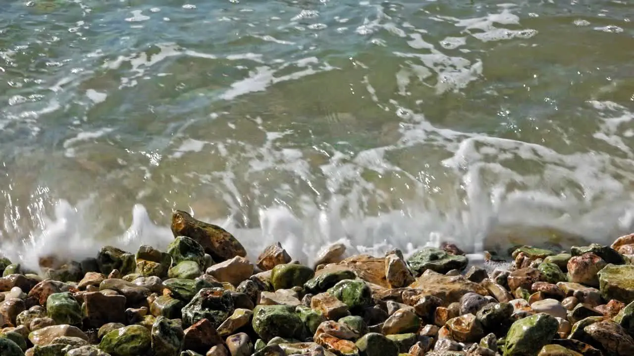 Clear waves splashing against the colorful rocks of the Jerusalem Beach