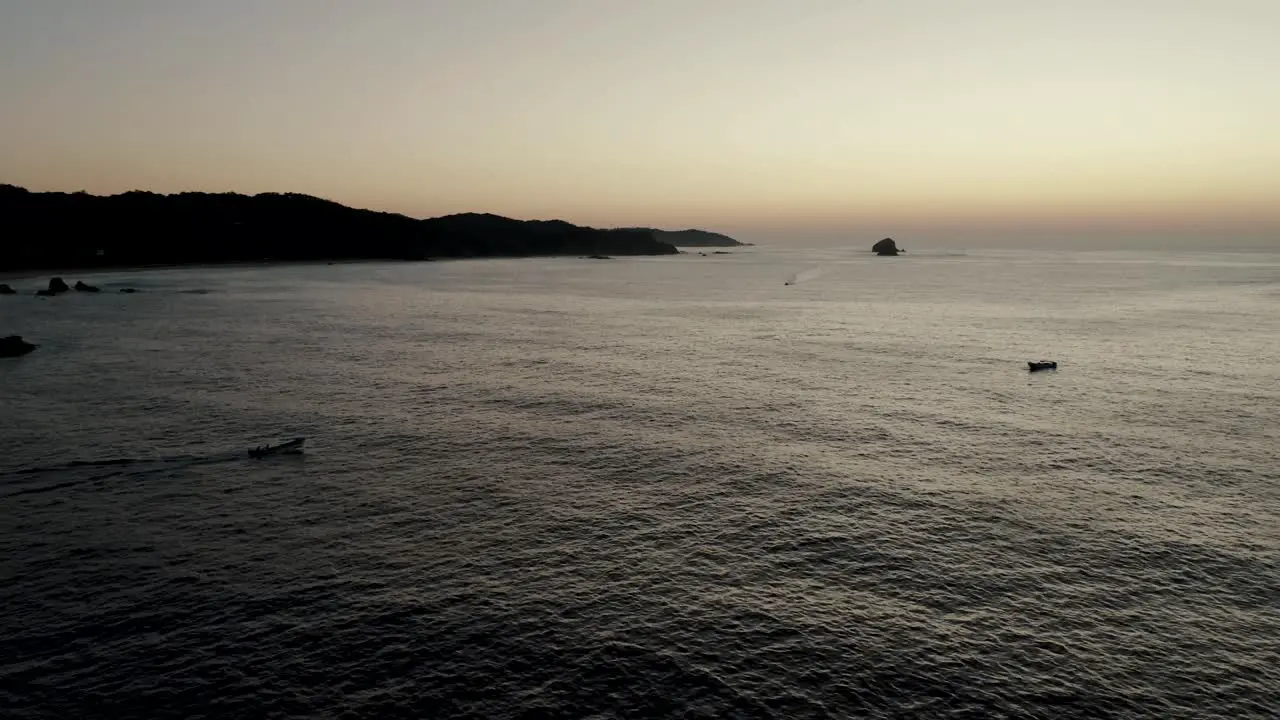 Silhouette Of Boat On Sea During Sunset In Mazunte Mexico aerial drone shot