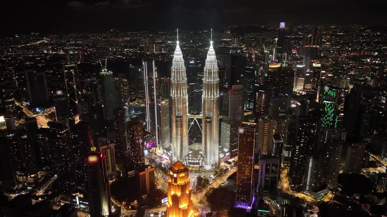 Aerial nighttime pull out shot of the Petronas Tower in the city of Kuala Lumpur