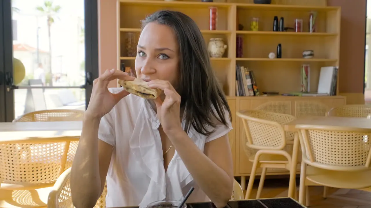 Vista Frontal De Una Mujer Morena Comiendo Pizza Sentada En Una Mesa De Restaurante Con Sus Amigos