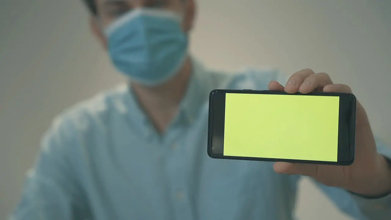 Hombre De Negocios Con Mascarilla Sosteniendo Un Teléfono Inteligente De Pantalla Verde