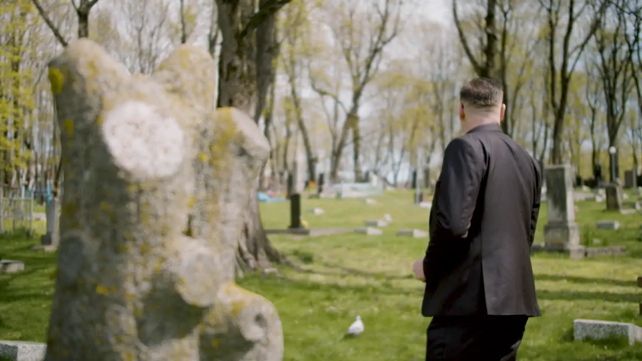 Hombre De Traje Negro Frente A Una Lápida En Un Cementerio