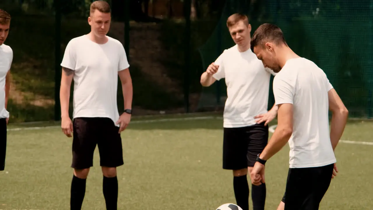 Ein Junger Fußballer Trainiert Freestyle-Tricks Auf Einem Straßenfußballplatz Während Sein Team Ihn Beobachtet 1