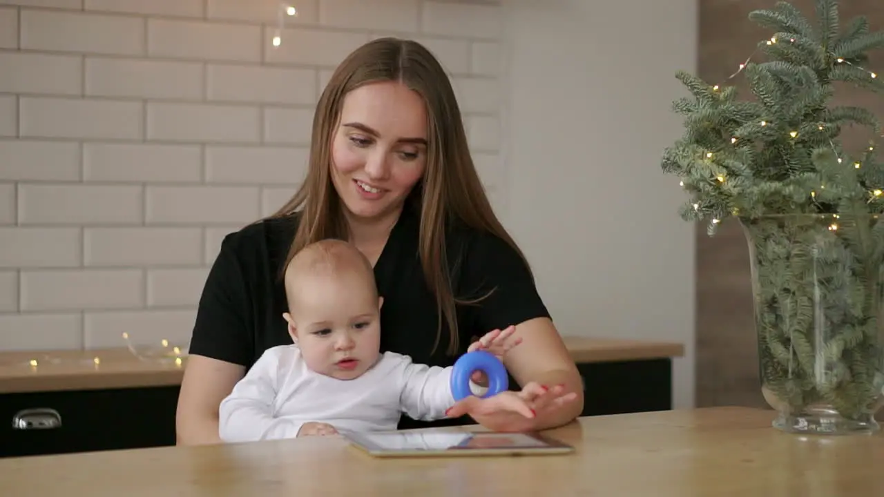 mother and baby are looking to play and read tablet computer on the couch at home