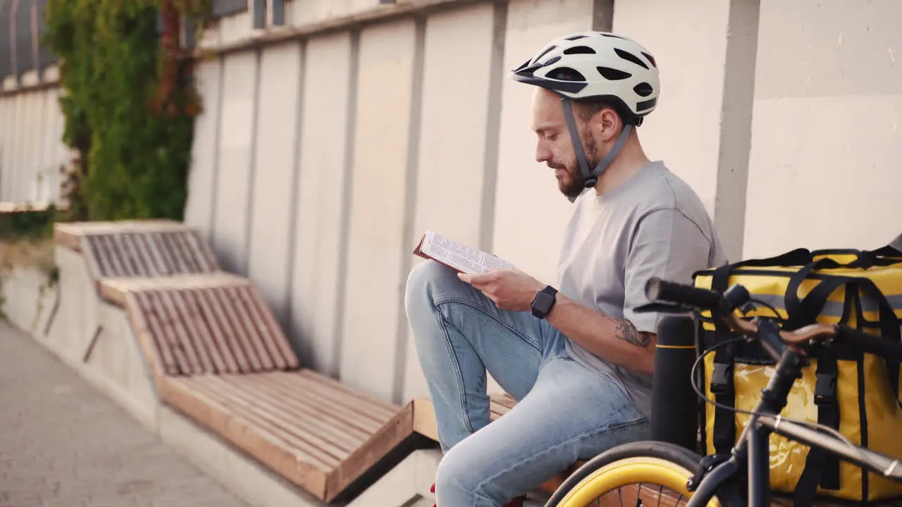 Food Delivery Man Reads A Book While Waiting For The Next Order