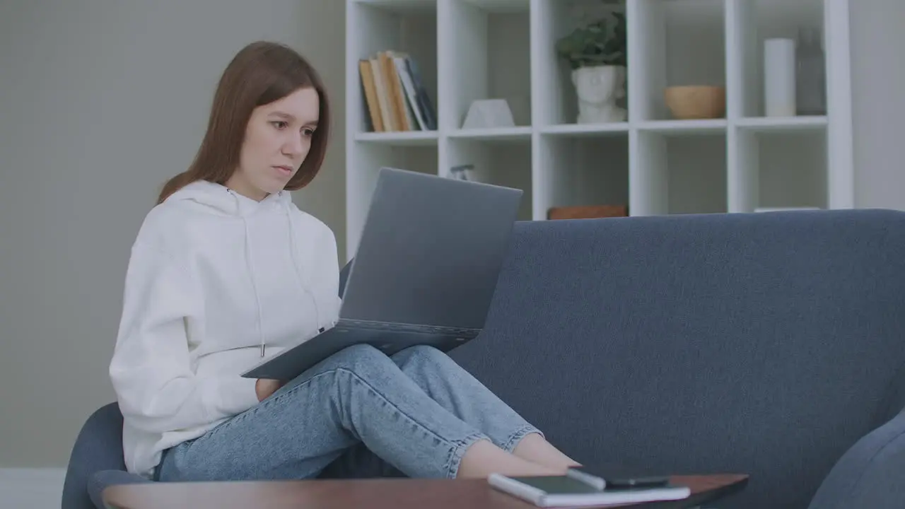 Woman using laptop on couch at home Thoughtful young woman sitting with computer on couch looking outside concentrate on work feeling bored need additional motivation working remotely at home