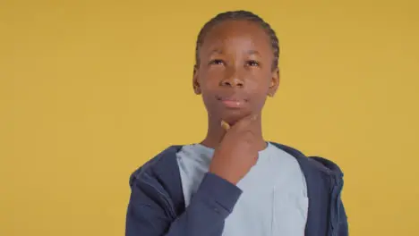 Studio Portrait Of Young Boy Thinking Against Yellow Background 2