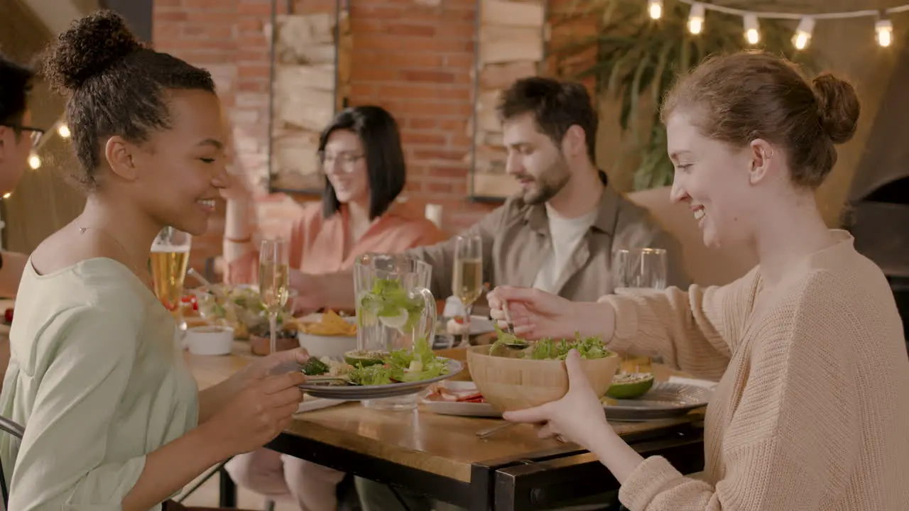 Young Woman Serves Salad To An Youg Female