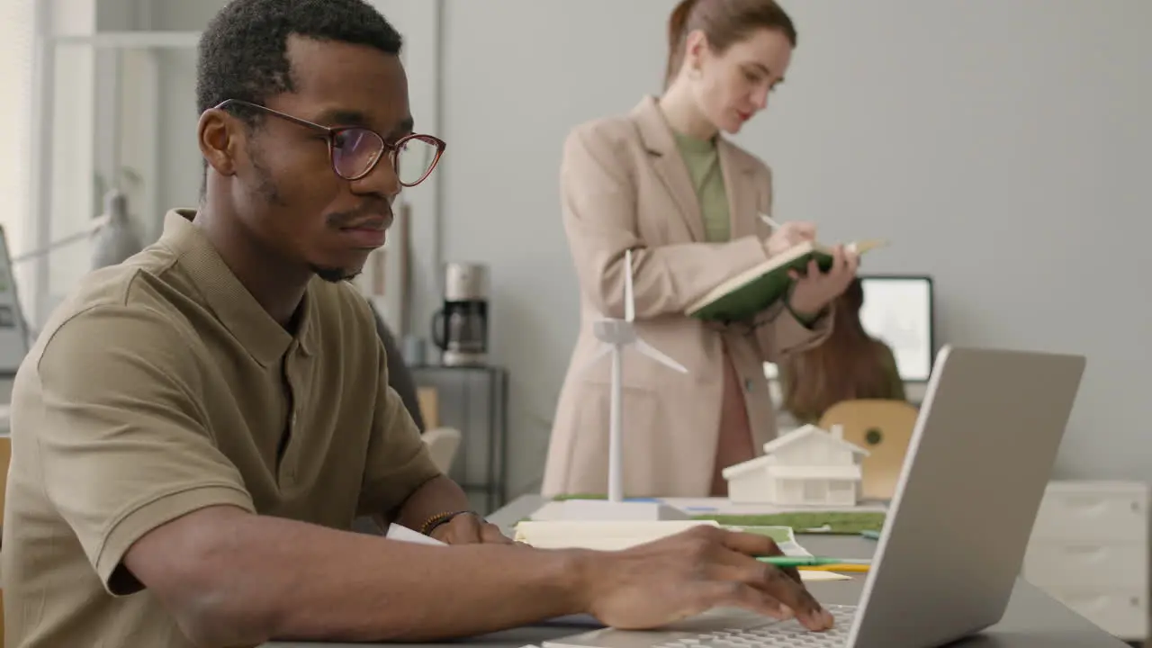 Man Working On A Project Sitting At Desk With Laptop In The Office