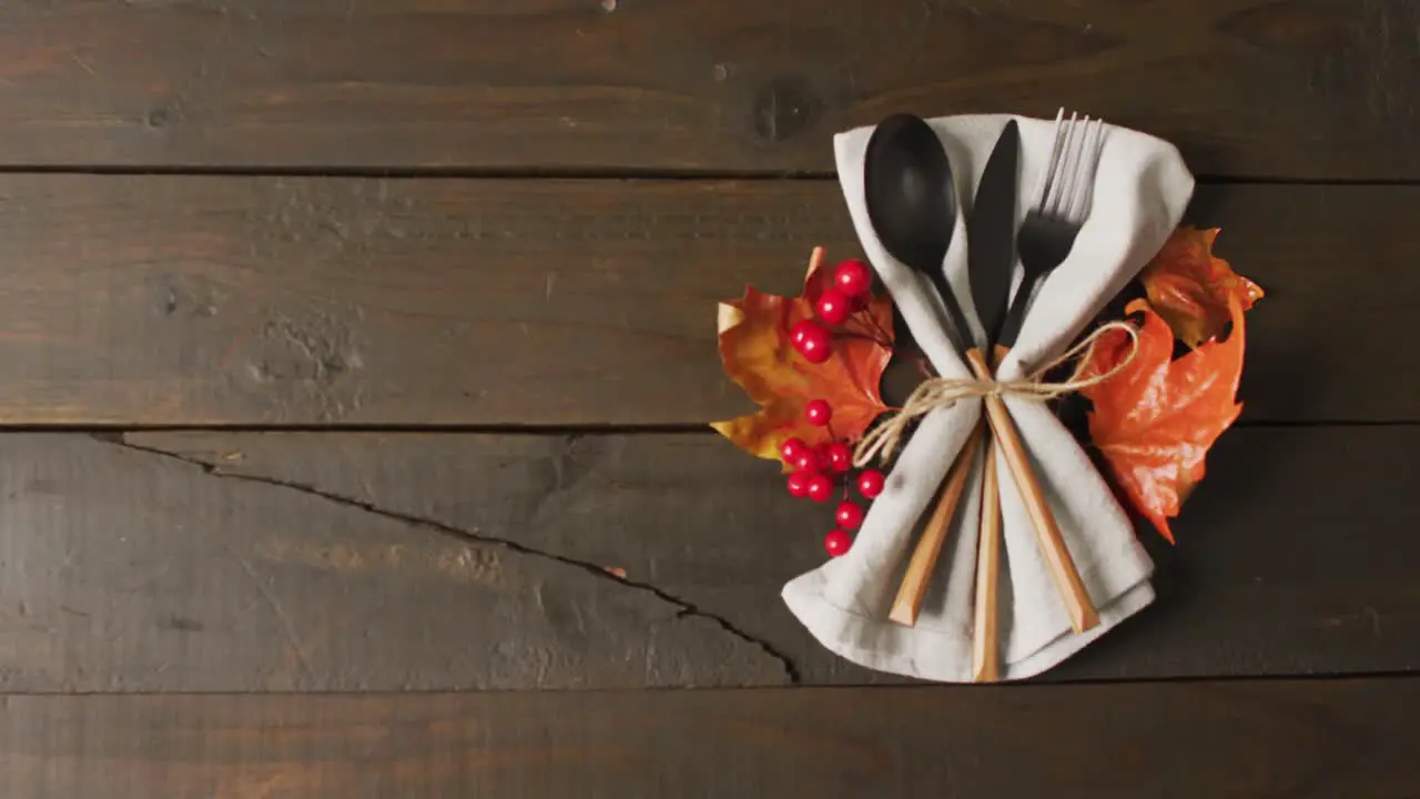 Video of cutlery cloth and autumn decoration lying on wooden surface