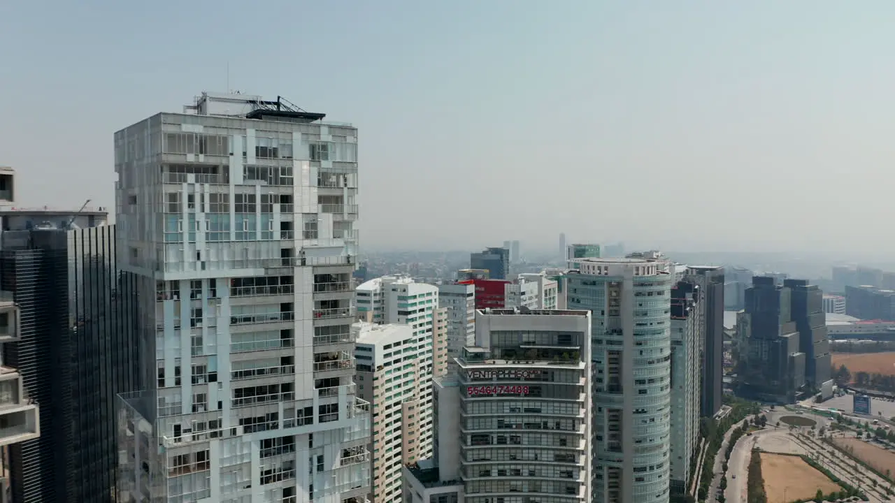 Forward fly above group of skyscrapers Camera tilt down on multilane road with roundabout Mexico City Mexico