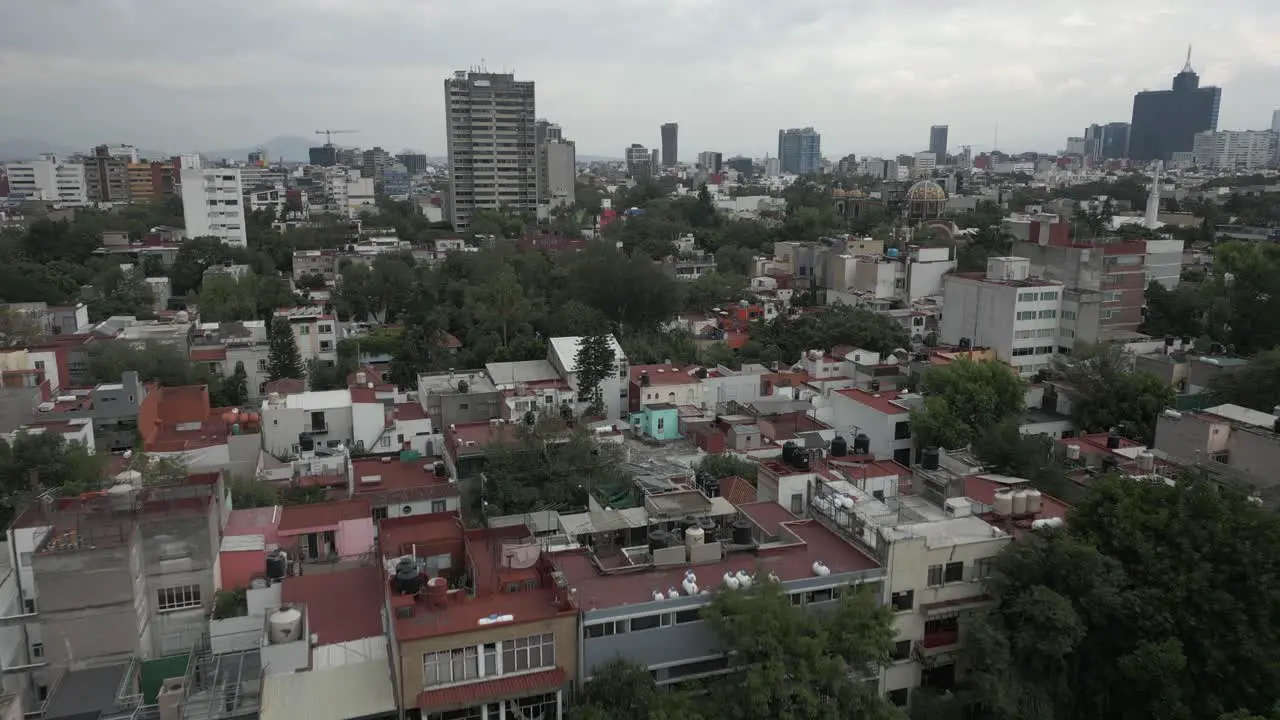 Low neighborhood flyover aerial buildings and trees in Mexico City