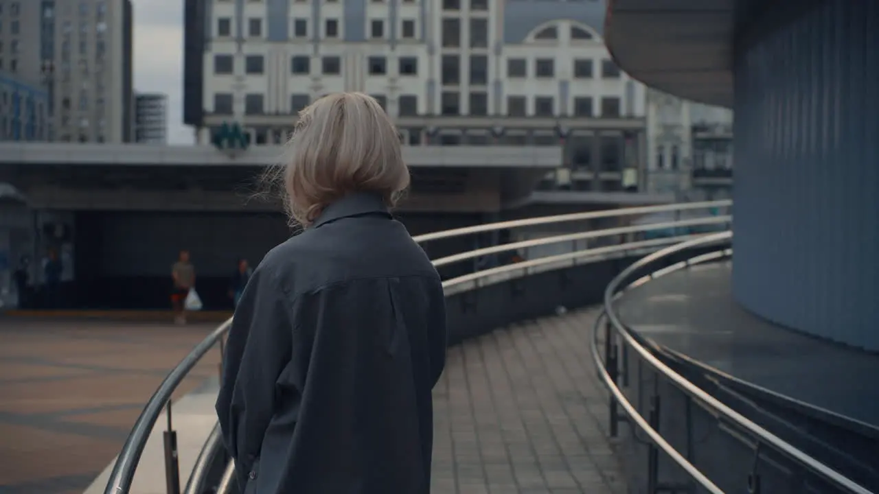 Blonde girl looking city view waiting for someone near urban buildings