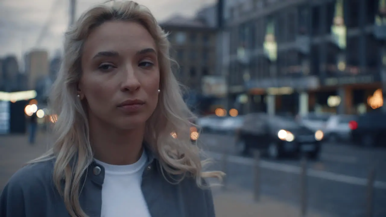 Young woman looking city view near road with passing cars at dusk