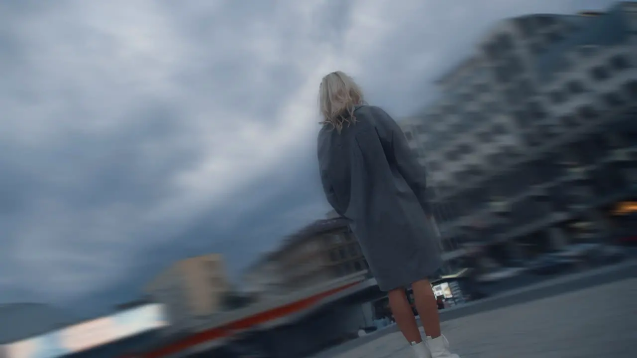 Blonde woman standing buildings at rainy city at evening urban area