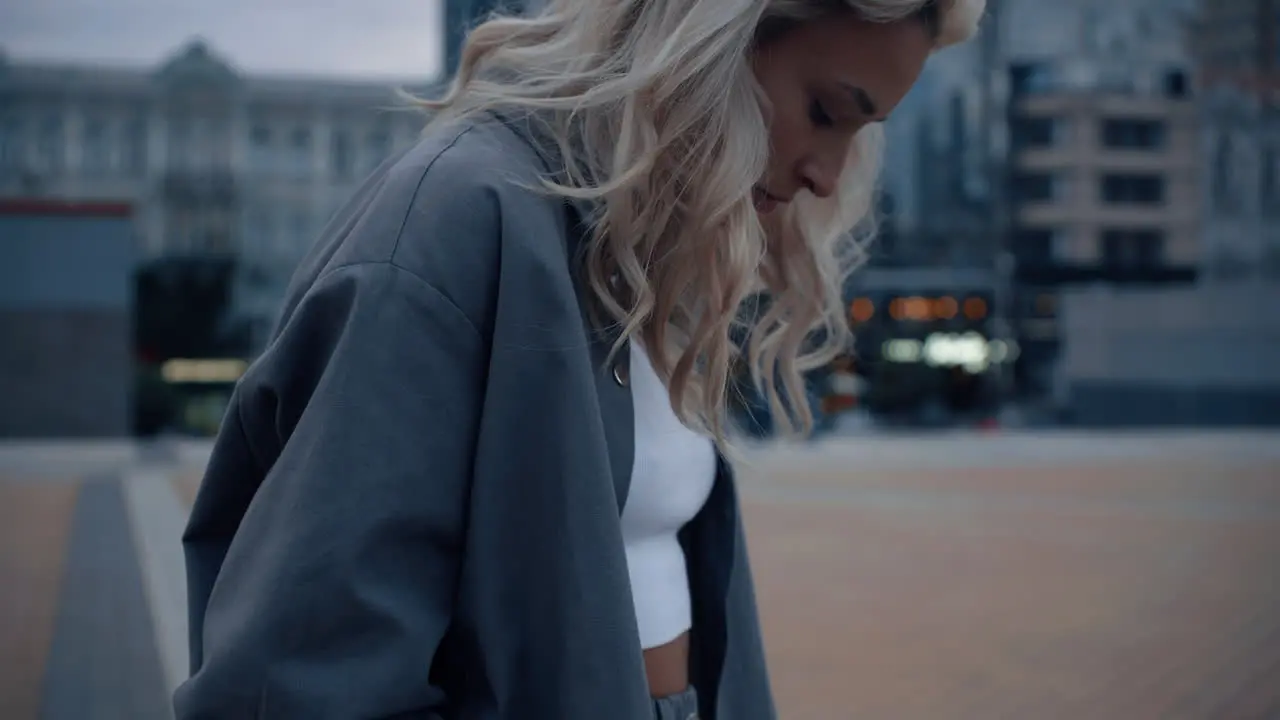 Blonde woman looking down in evening city urban background