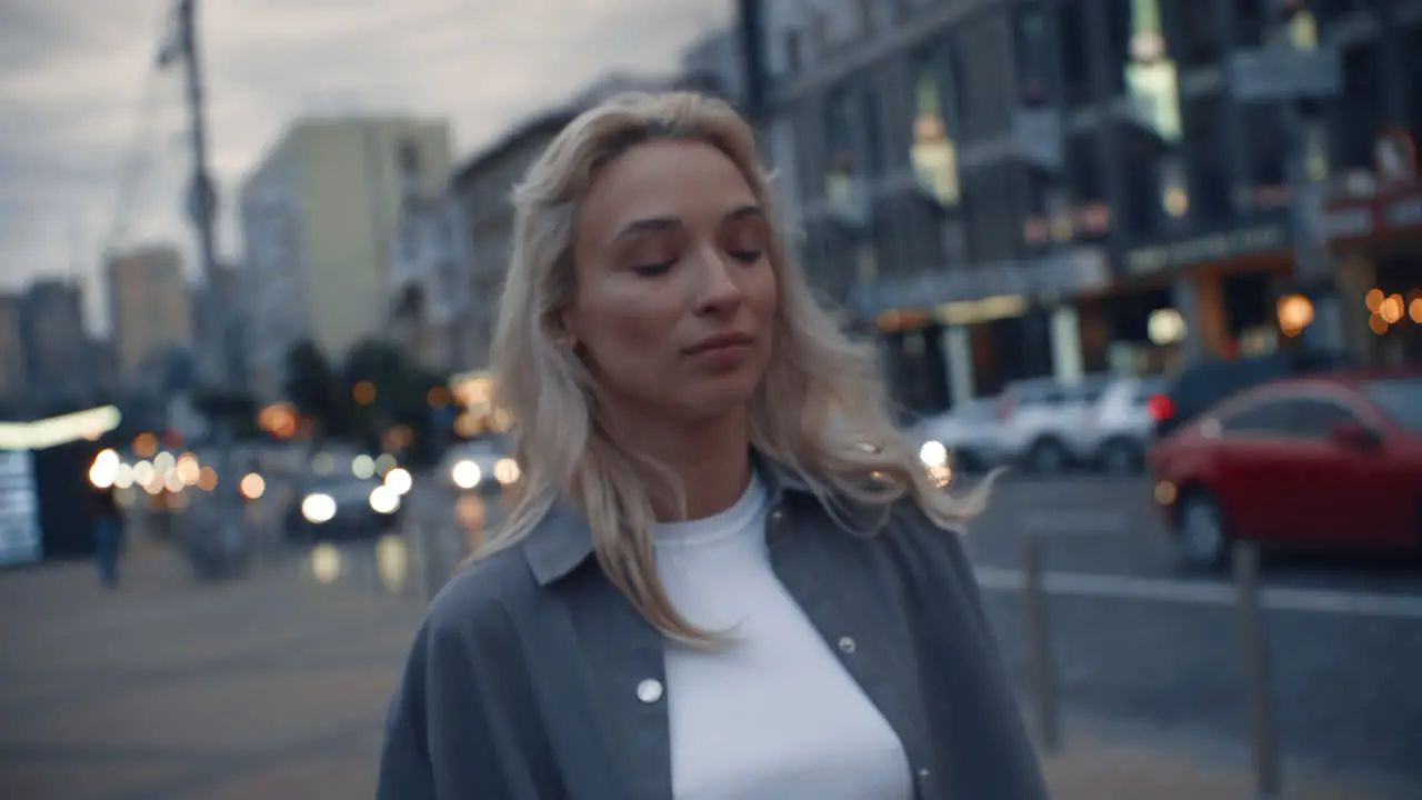 Charming woman walking city at evening near highway traffic lights