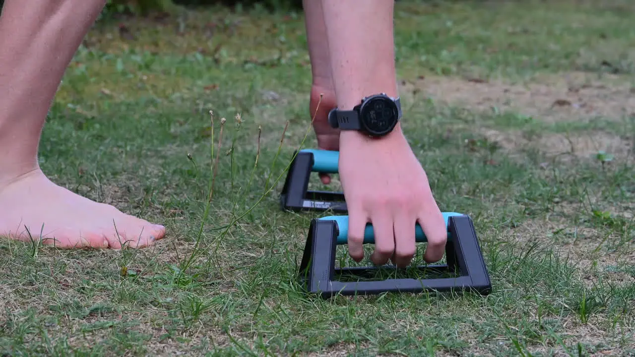 A young calisthenics athlete is preparing his hands on parallettes small bars to do pushups to grow his chest