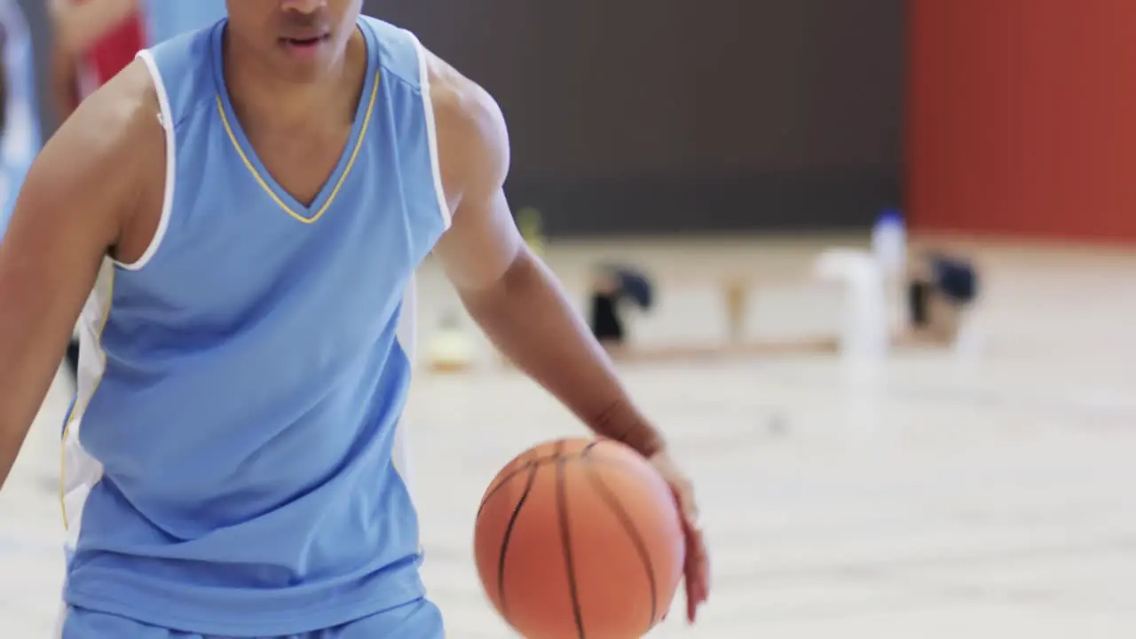 African american male basketball player bouncing ball during team training session on indoor court