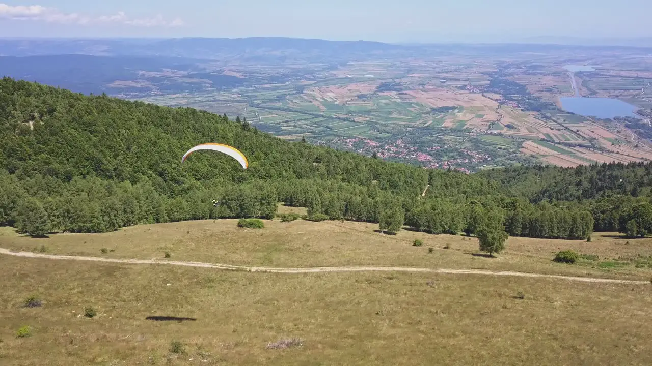 Paraglider flying very slow above forest