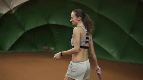 Smiling happy young woman in sportswear and long hair makes a wide serve ball in tennis Strong shot Slow motion