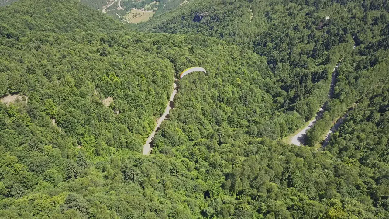 Paraglider flying over forest