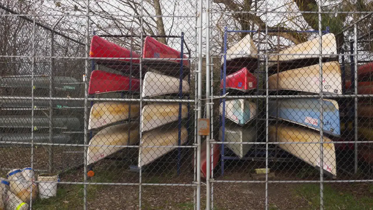 colorful Canoes stored stacked organized behind a locked fence during autumn fall off season at a city owned public park