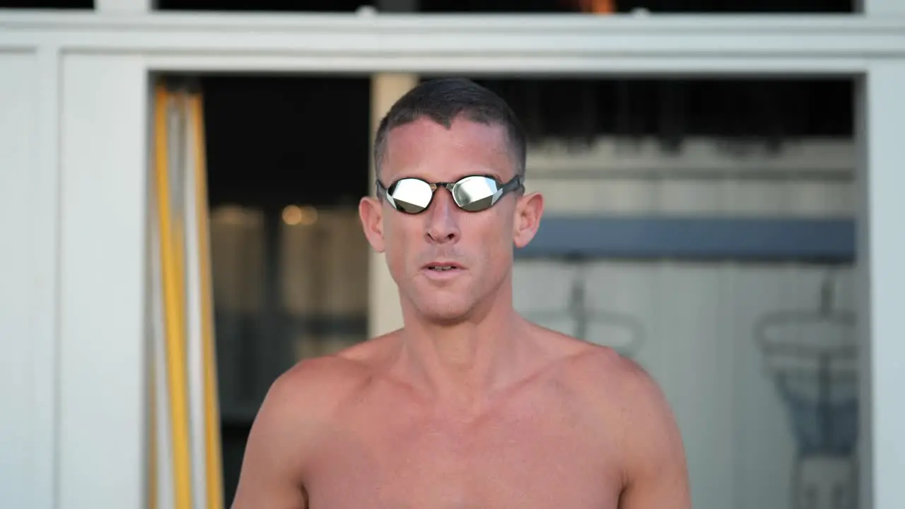 Young attractive swimmer puts on his swimming goggles frontal close up