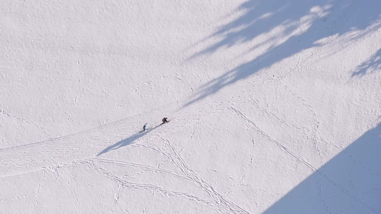 Drone flight with to skiing people at a snowy white winter track filmed straight from above couple sports at the cross country track