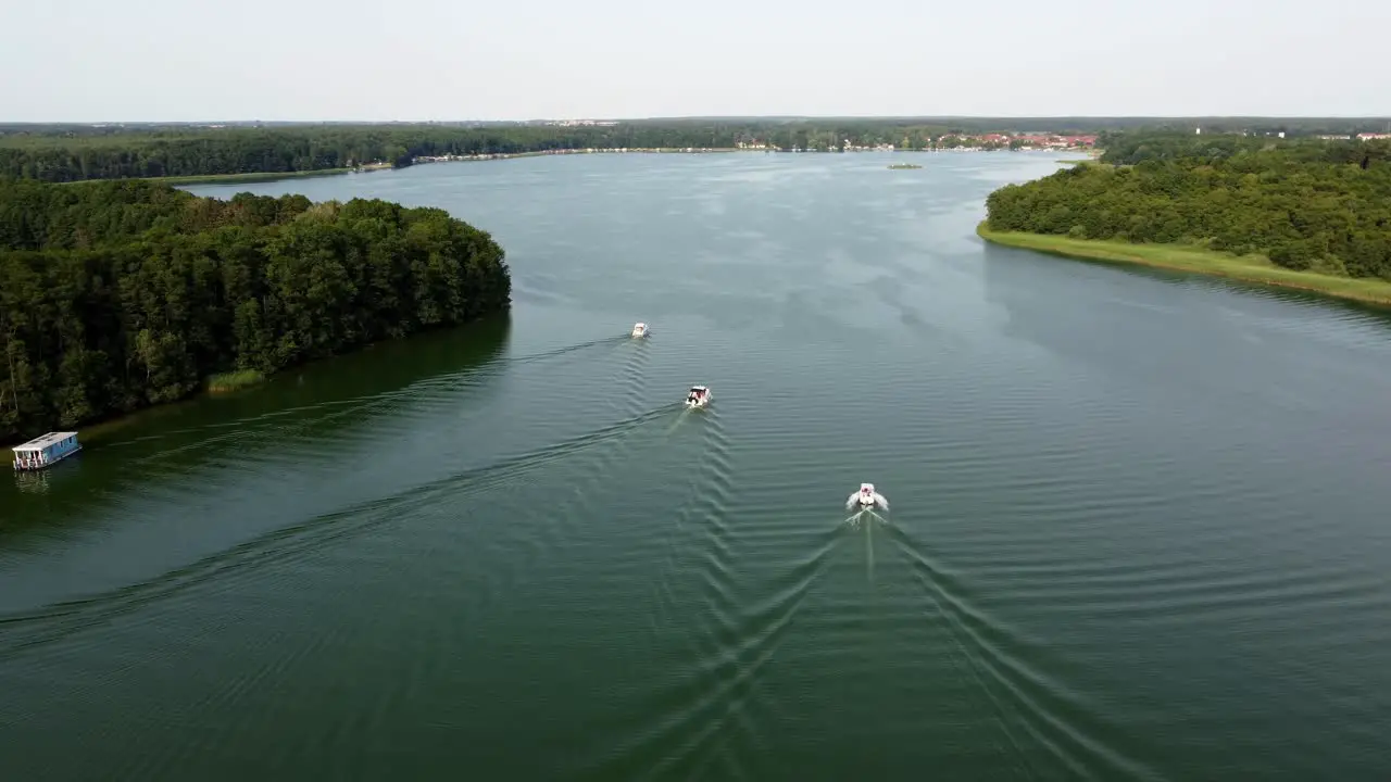 Three motor boats driving on a lake next to a forest in Brandenburg Germany