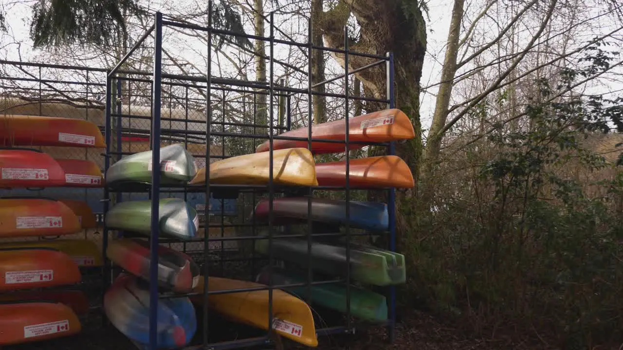 colorful orange red blue and green Canoes stored stacked organized on a metal rack during autumn fall off season