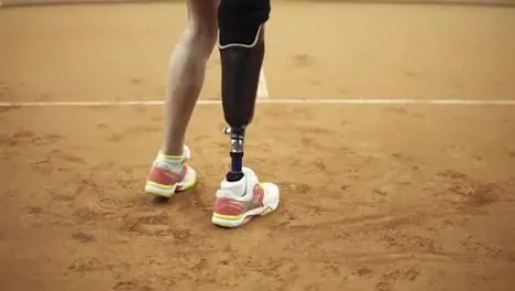 Footage from the bottom up of a sports long haired woman with a physical disability playing tennis Close up