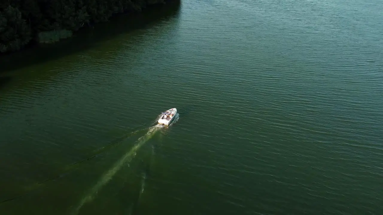 Small motor boat driving on a lake next to a forest in Brandenburg Germany