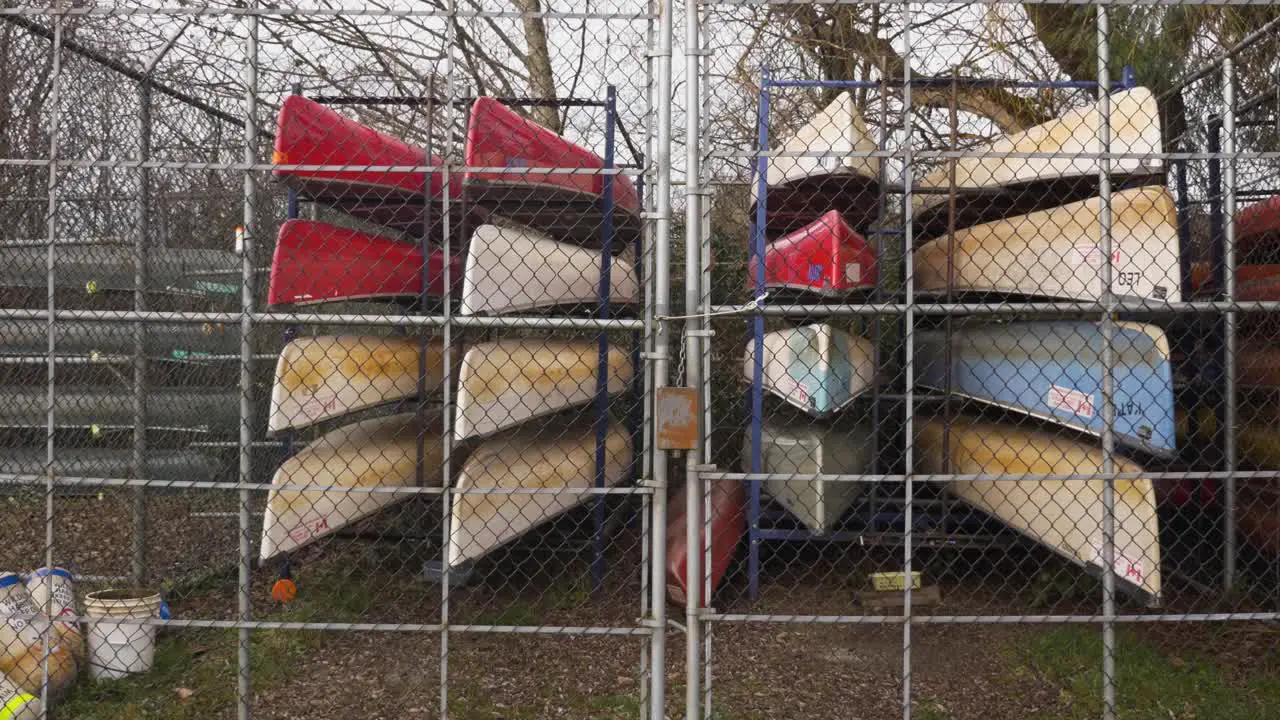 Canoes stored stacked organized behind a locked fence during autumn fall season