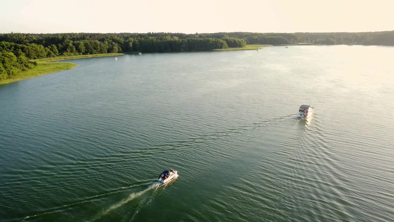 Two motor boats driving on a large natural lake during sunset in Brandenburg Germany