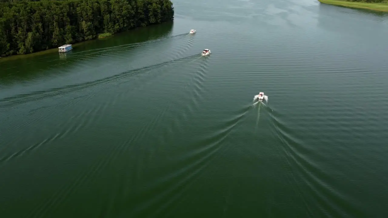 Several motor boats driving on a lake next to a forest in Brandenburg Germany