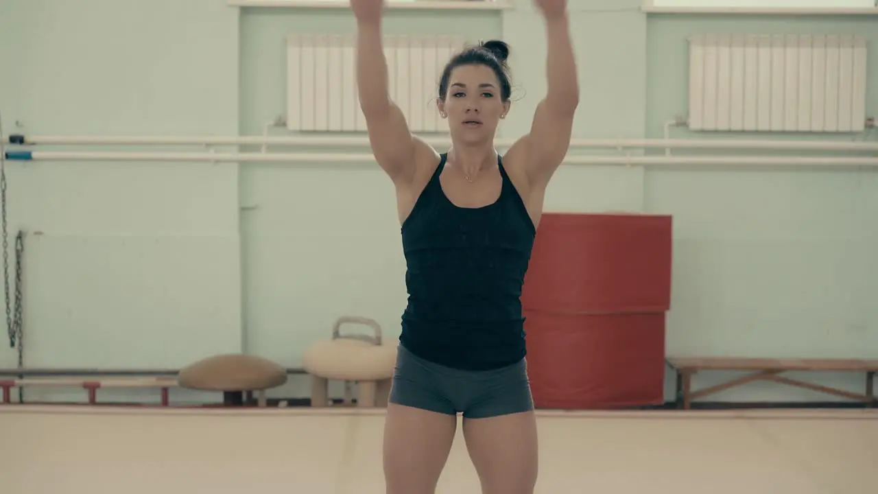 Athletic girl in gym doing warm-up of arm muscles