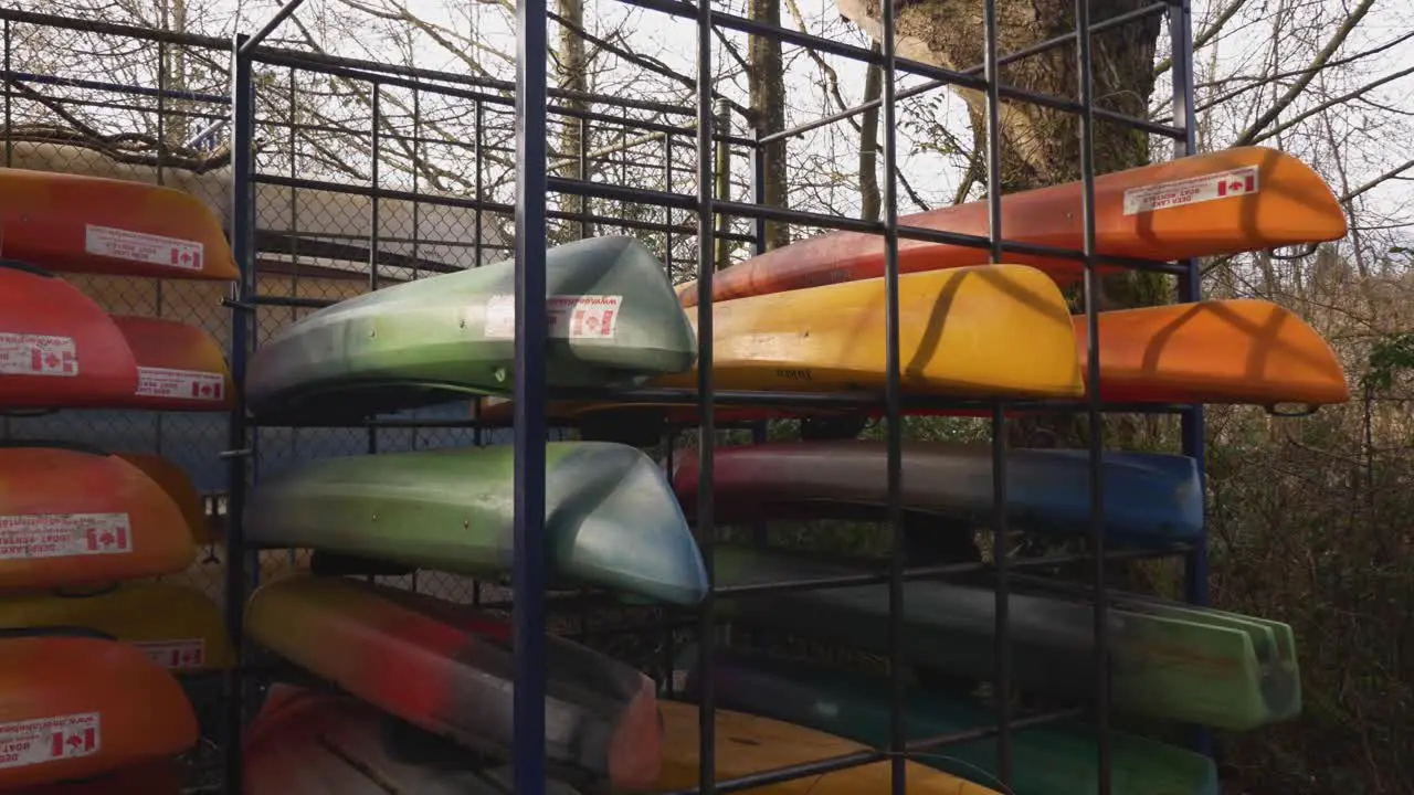 colorful Canoes with canadian flag sticker stored stacked organized behind a locked fence during autumn fall off season at public park facility