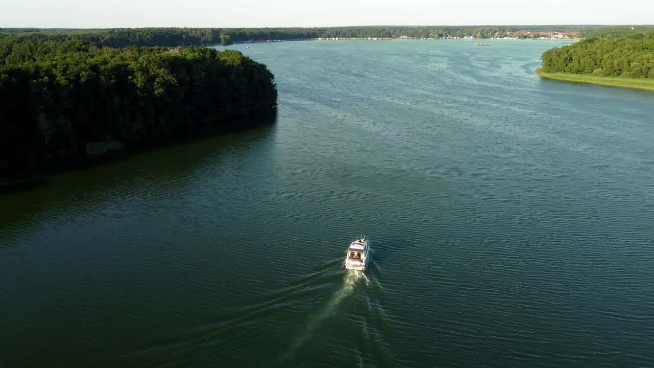 Small yacht driving on a lake surrounded by a forest in Brandenburg Germany