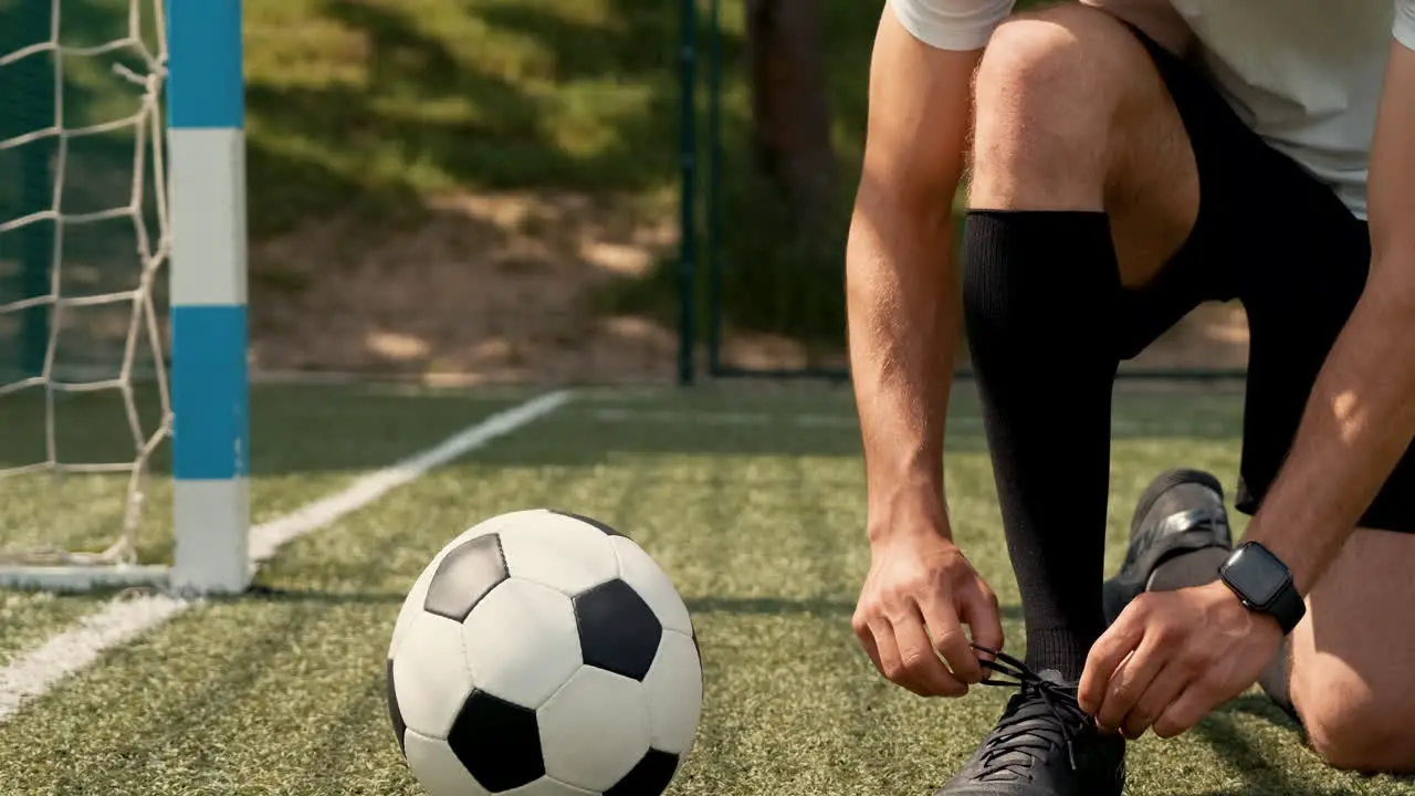 Close Up Of An Unrecognizable Football Player Tying His Soccer Shoes On A Street Football Pitch 1