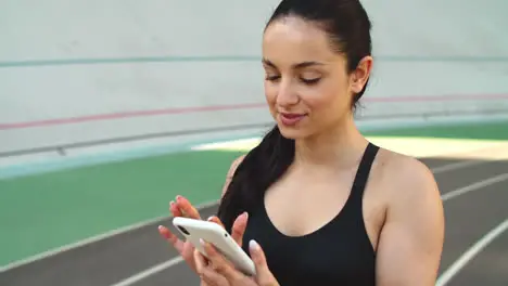 Sporty girl using mobile phone at stadium Ssport woman checking results