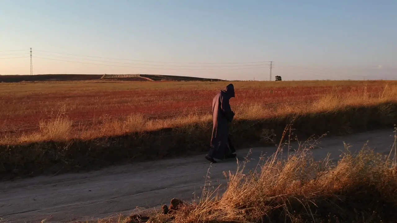 A sideways shot following a monk walking on a dirt road