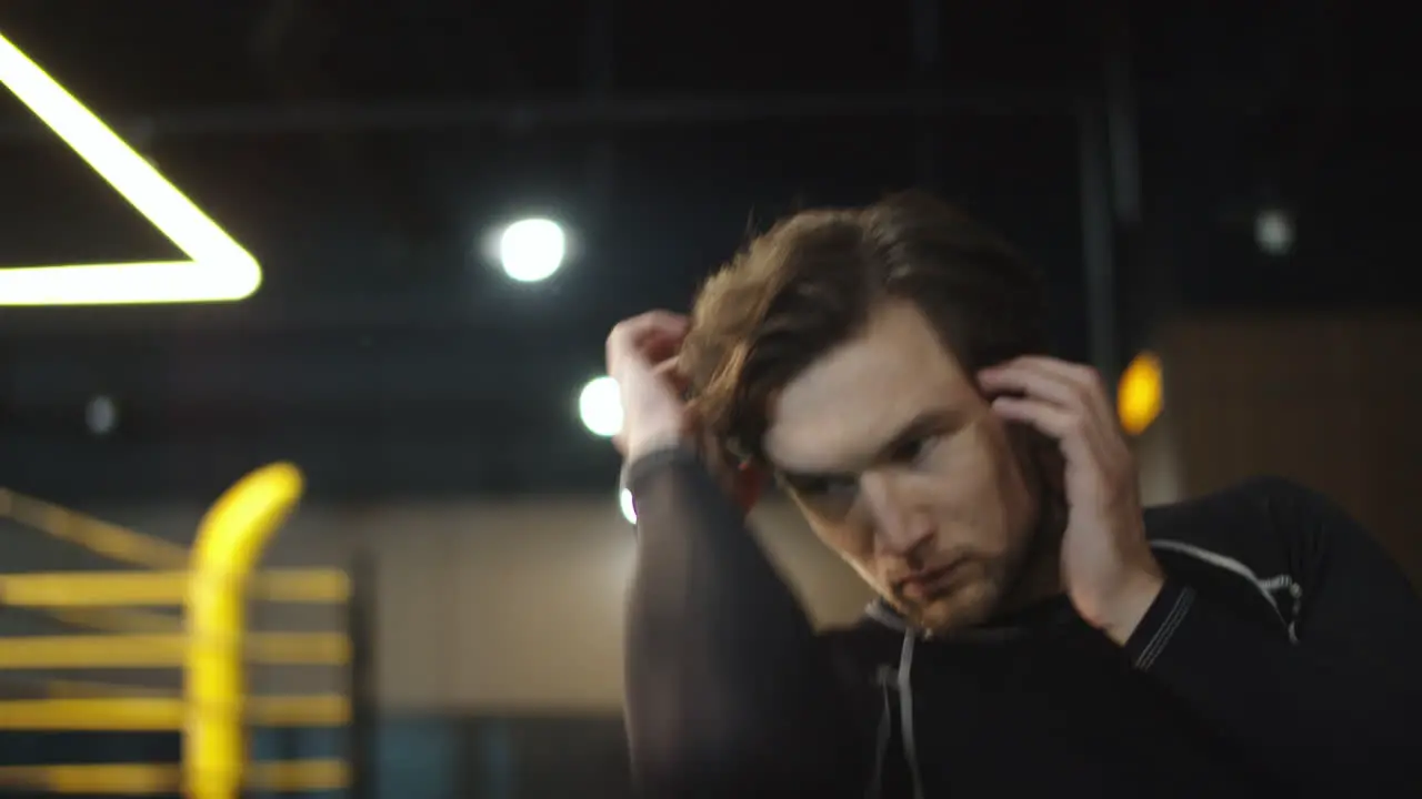 Handsome male athlete exercising at gym Boxer warming up hands in sport club