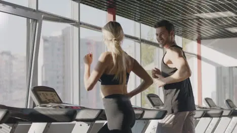 Running couple training cardio exercise on treadmill machine in fitness center