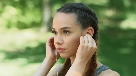 Sport woman listening music in earphones at outdoor workout