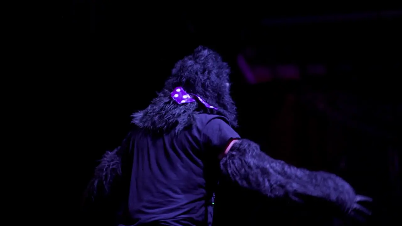 A performer in gorilla costume dancing in front of a crowd in a club