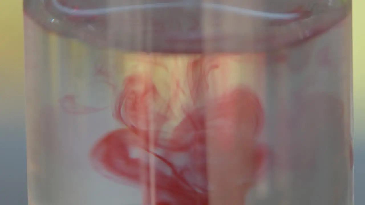 Super close up macro of a test tube with a water sample then adding pink or red drops to test for the PH level which results in a chemical reaction