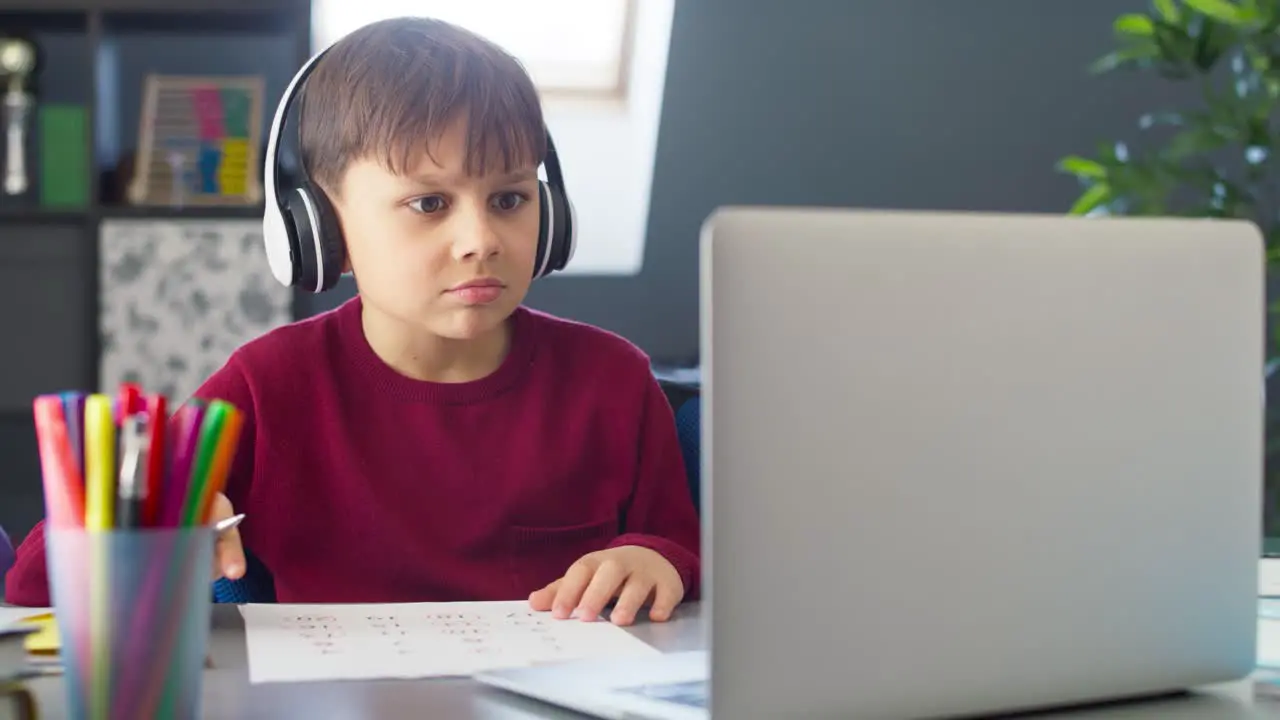 Handheld video of boy with headphones during remote learning at home