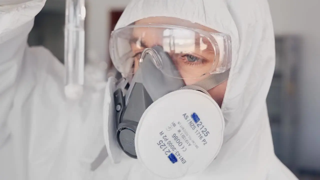 scientist in a protective suit and a respirator examining a substance in a test tube